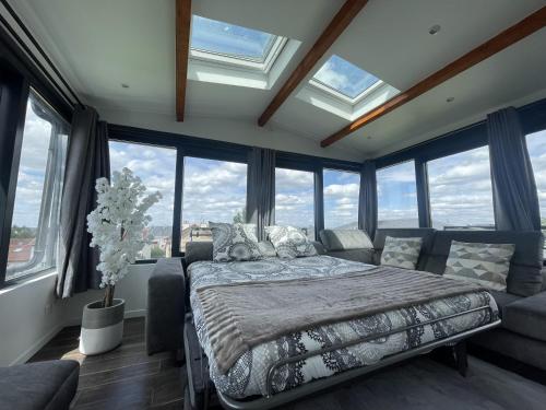 1 dormitorio con cama, sofá y ventanas en Appartement T2, très cosy, vue panoramique, en Saint-Cyr-lʼÉcole