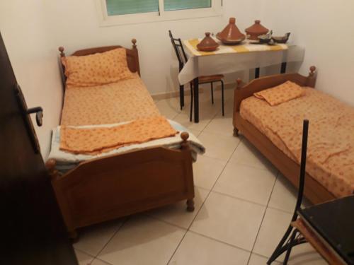 two beds in a room with a table and a tableablishangering at Ksiba in Salé