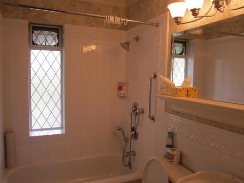 a bathroom with a tub and a toilet and a window at Heathergate Cottage and Suites in Victoria