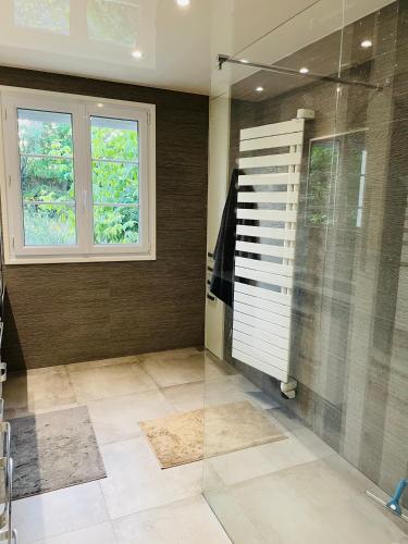 La salle de bains est pourvue d'une douche en verre et d'une fenêtre. dans l'établissement Maison des Coteaux blancs, à Chaudefonds-sur-Layon