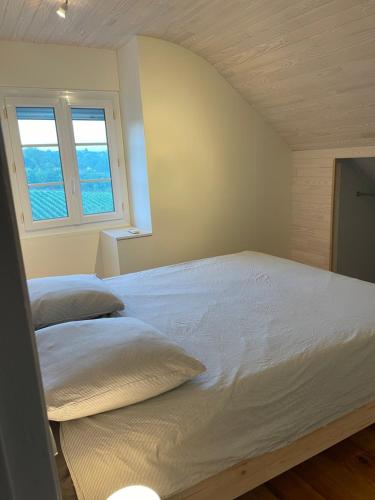 a bedroom with a large bed with two pillows at Maison des Coteaux blancs in Chaudefonds-sur-Layon