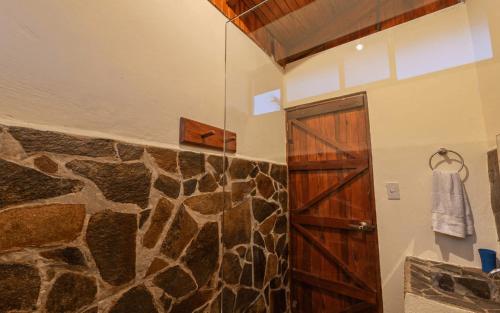 a bathroom with a shower with a wooden door at Vista Lago Arenal in Piedras