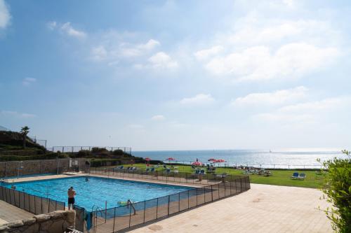 a swimming pool with the ocean in the background at Seaview Stylish Apartment with Balcony in Herzliya