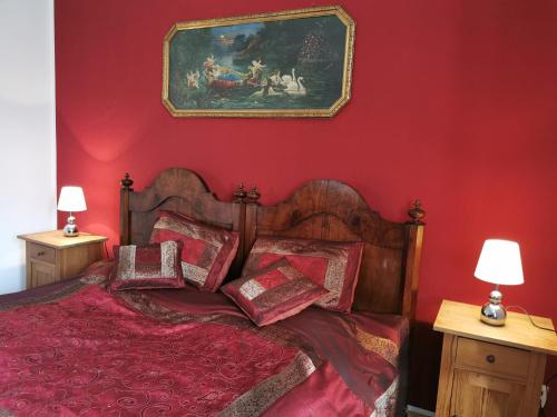 - une chambre rouge avec un lit et un tableau mural dans l'établissement Ruhige Ferienwohnung im Gutshaus, à Niederorschel