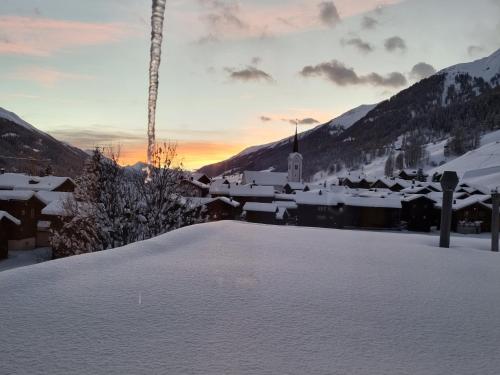 a snow covered town with a church in the mountains at Hotel Astoria in Ulrichen