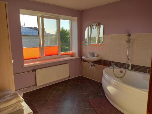a bathroom with a bath tub and a sink at Spacious & Cozy Apartment with Forest View in Zapyškis