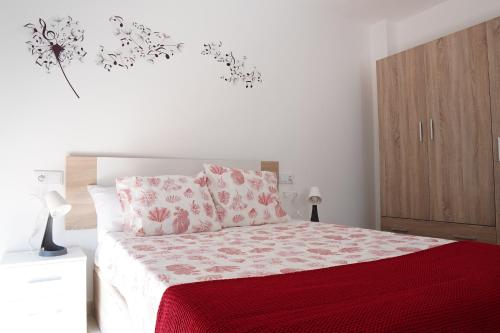 a bedroom with a bed with a red comforter at APARTAMENTOS TURÍSTICOS SAN MIGUEL ARCÁNGEL, S.L. in San Roque