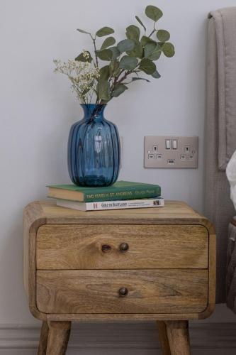 a blue vase sitting on top of a wooden table with books at The Arran, St Andrews in St. Andrews