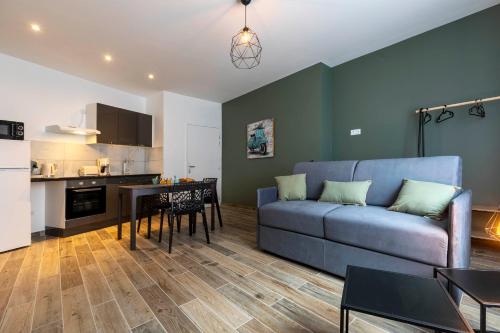 un salon avec un canapé bleu et une cuisine dans l'établissement LOC TROTTEUR LE ROMARIN Gare SNCF de Lourdes, à Lourdes