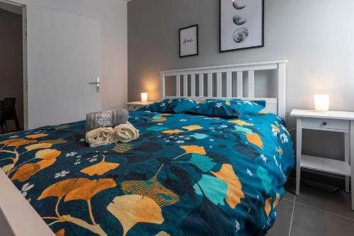 une chambre avec un lit avec une couette colorée dans l'établissement LOC TROTTEUR LE GRAPHITE T2 Grand confort Terrasse, à Lourdes