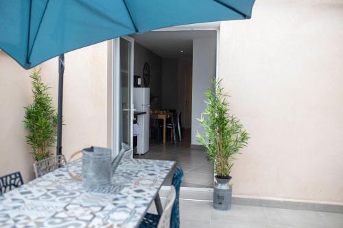 une table avec un parapluie bleu et deux plantes en pot dans l'établissement LOC TROTTEUR LE GRAPHITE T2 Grand confort Terrasse, à Lourdes