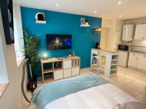 a living room with a blue wall and a kitchen at ☆ Les pieds sur terre ☆ tout confort ☆ NETFLIX ☆ in Metz