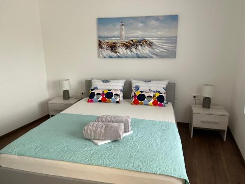 - une chambre avec un grand lit blanc et des oreillers dans l'établissement Apartmani Anloma Lorainne, à Povljana