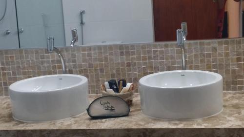 two white bowls on a counter in a bathroom at Oasis Tajaja Pousada in Jacumã