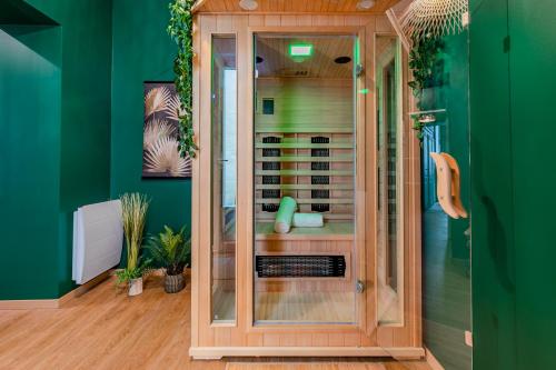 a glass shower in a green room with green walls at Appartement Jungle - Libourne Centre - 4 pers - Sauna - Netflix in Libourne