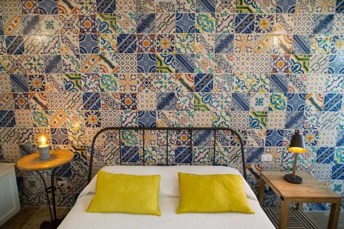 a bed with two yellow pillows in a room with tiles at meridiano12 in Favignana