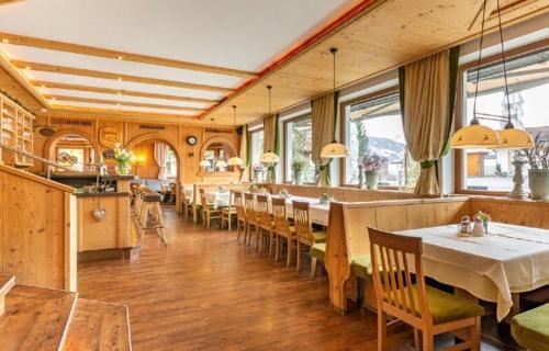 a dining room with tables and chairs and windows at Restaurant Gästehaus Wiesenheim in Uderns
