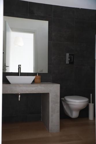 a bathroom with a sink and a toilet and a mirror at Casa Lupita in Favara
