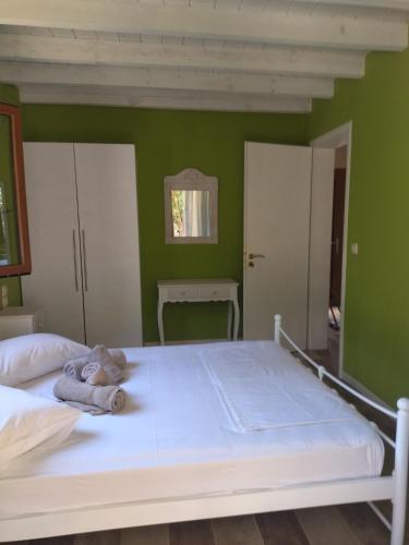 a bedroom with a white bed with green walls at Theonymfi Luxury Villas in Doukádes