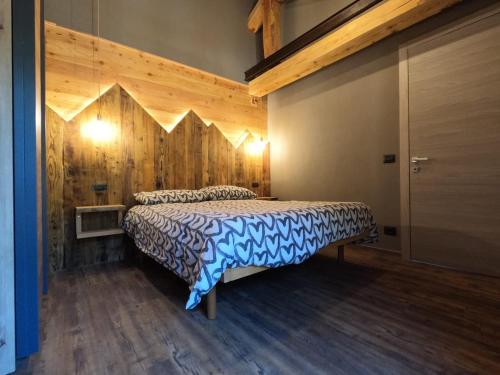 a bedroom with a bed with a wooden wall at Appartamenti il bersaio Alloggio 3 in Sambuco