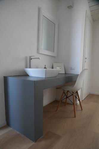 a bathroom with a white sink and a chair at Casa Lupita in Favara