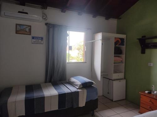 ein kleines Schlafzimmer mit einem Bett und einem Fenster in der Unterkunft Suites Pouso Familiar José e Maria in Paraty