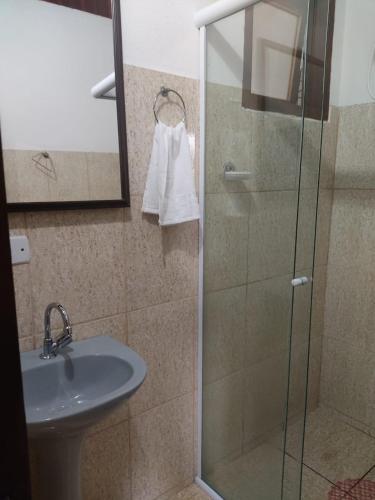 a bathroom with a sink and a glass shower at Suites Pouso Familiar José e Maria in Paraty