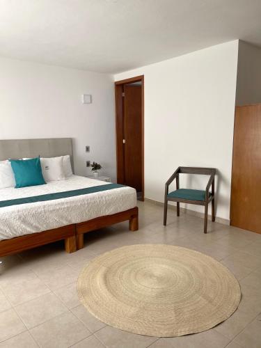 een slaapkamer met een bed, een stoel en een tapijt bij AZUL ARENA Hotel Boutique in Mazatlán