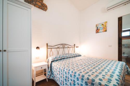 a white bedroom with a bed with a blue comforter at Agriturismo Irghitula in Posada