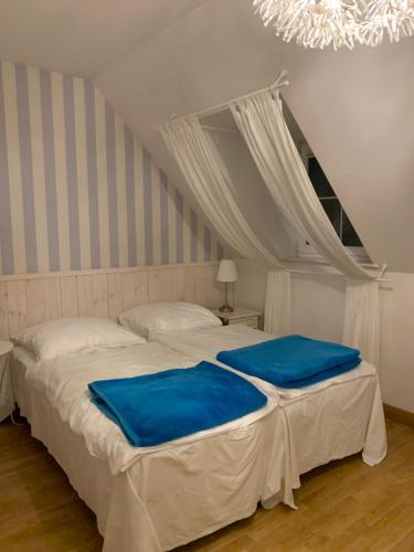 a bedroom with two beds with blue sheets and a chandelier at Pokoje Pinokio in Darłowo