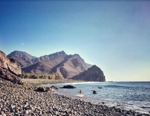 a group of people in the water on a rocky beach at Casa en La Ladera - Real vibe - Beach & Mountain in La Aldea de San Nicolas