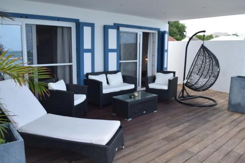 a patio with chairs and a hammock on a balcony at Tradewinds Apartments Simpson Bay in Simpson Bay