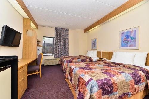 a hotel room with two beds and a desk and a television at America's Best Value Inn & Suites, Atlanta - Morrow in Morrow