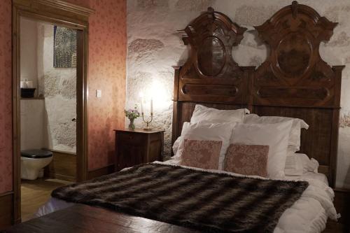 a bedroom with a large wooden bed with pillows at Domaine du Très-Haut - Château de Montanges in Montanges