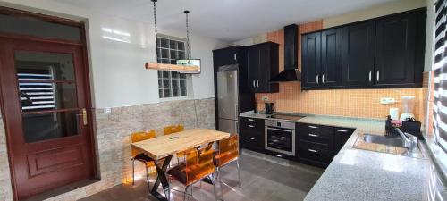 uma cozinha com armários pretos e uma mesa de madeira em Casa con encanto em Cariño