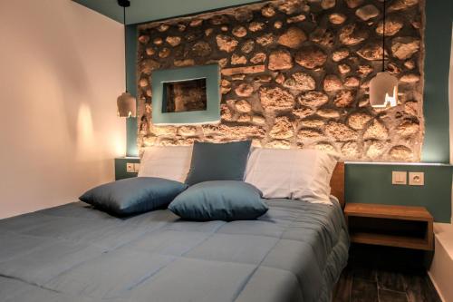 a bedroom with a stone wall and a bed with pillows at Avli Luxurious House in Kalabaka