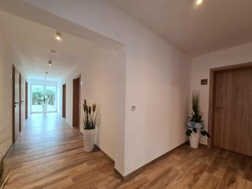 an empty hallway with two vases with plants in it at Hotel Pension Nordzeit in Norddeich