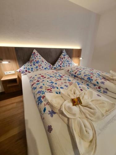 a bed with white sheets and flowers on it at Hotel Pension Nordzeit in Norddeich