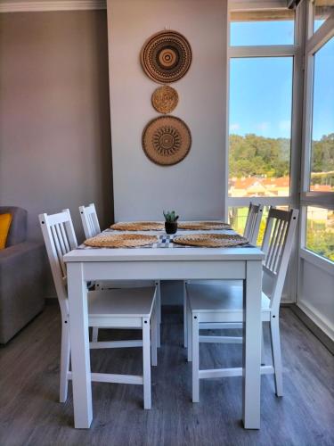 a white table and chairs in a room with a window at O Vendaval in Corcubión