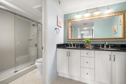 een badkamer met een wastafel, een toilet en een spiegel bij Beach Cottages 1504 in Clearwater Beach