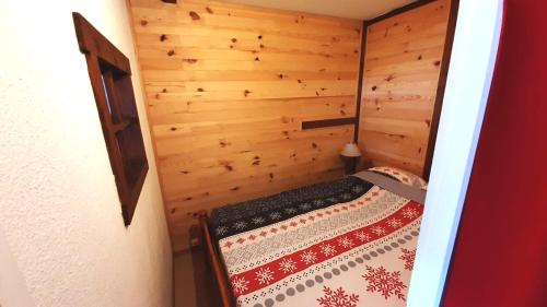 a small bedroom with a bed in a wooden room at Au Doubs Refuge in Métabief