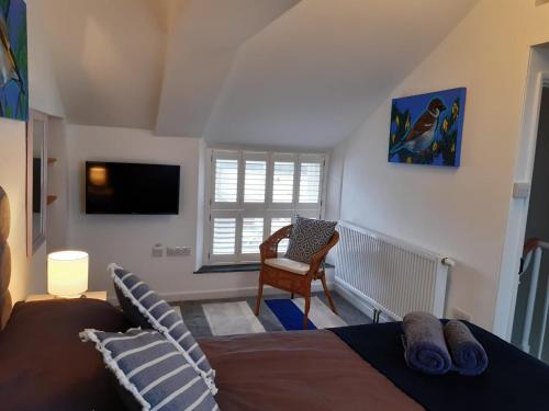 a bedroom with a bed and a chair and a television at Sanderling - Grade 2 Listed Georgian Townhouse by the sea in Penzance
