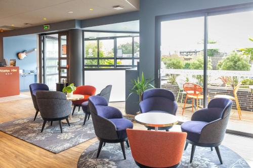 a waiting room with chairs and tables and windows at Best Western Hotel Atlantys Zenith Nantes in Saint-Herblain