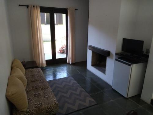 a living room with a fireplace and a television at Pousada Vênus in Monte Verde