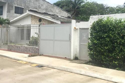 a white gate in front of a house at Habitación independiente cerca al mar. in Puerto Salgar