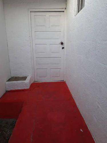 un camino rojo que conduce a una puerta blanca con suelo rojo en Habitación independiente cerca al mar., en Puerto Salgar
