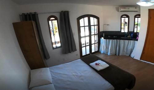 une chambre avec un lit dans une pièce avec des fenêtres dans l'établissement Melhores Suítes, à Arraial do Cabo
