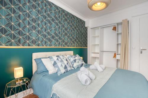 a bedroom with a blue bed with white pillows at Le Somptueux aux portes de Paris PARKING Gratuit in Bagneux