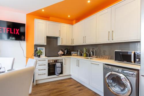 uma cozinha com armários brancos e um tecto laranja em Bright cheery 4 bd apartment by Brighton Station em Brighton & Hove