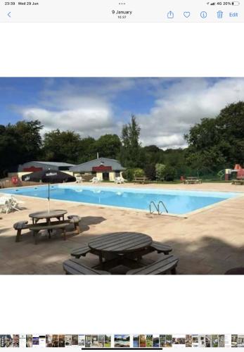 a picture of a swimming pool with two picnic tables at CRIB GOCH HOLIDAY CABIN SNOWDONIA in Caernarfon